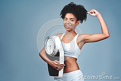 Im getting stronger and more confident by the day. Studio shot of an attractive young woman holding a weight scale. Stock Photo