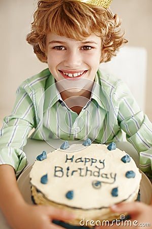 Im just here for the cake. Portrait of a cute little boy sitting by his birthday cake. Stock Photo