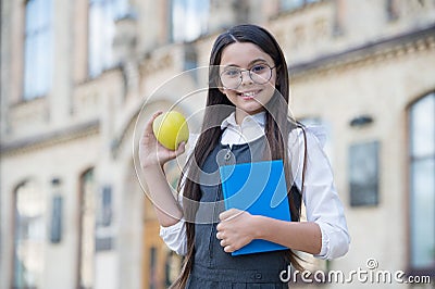 Im loving it. Happy child hold apple and book. School snack. Snack break. Healthy eating and snacking. Vegetarian food Stock Photo