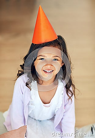 Im ready, wheres the party. Portrait of a cute little girl wearing a party hat at home. Stock Photo