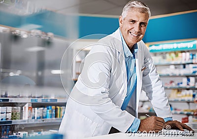 Im in the service of bettering lives. a male pharmacist writing on a clipboard in a drugstore. Stock Photo