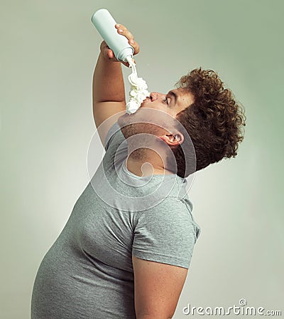 Im on the whipped cream diet. an overweight man filling his mouth with whipped cream. Stock Photo
