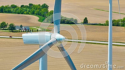 Aerial drone shot of wind turbines and blades with farmland below and house in distance Stock Photo