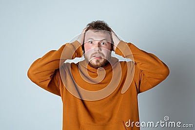 Image of anxious bearded young man start to panic, looking at camera with worried expression, standing in stylish hoodie Stock Photo