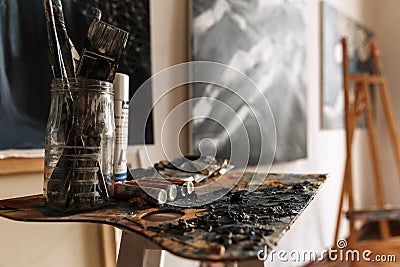 Image of artist workplace with painting tools and artworks on wall Stock Photo