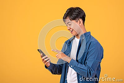 Image Asian man standing on orange background Using a mobile phone Stock Photo