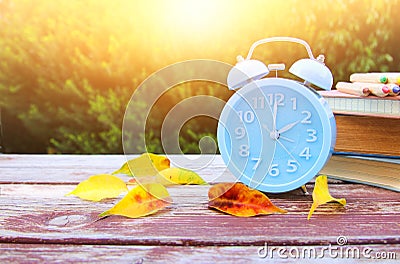 Image of autumn Time Change. Fall back concept. Dry leaves and vintage alarm Clock on wooden table Stock Photo