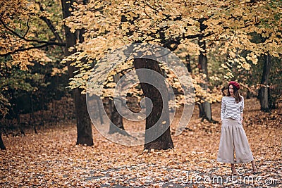 Image of a beautiful brunette woman in a red beret walks in the park in autumn Stock Photo