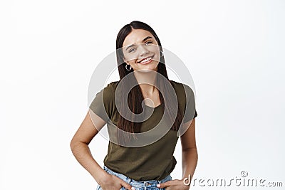 Image of beautiful healthy woman with candid smile, standing relaxed against white background, looking happy at camera Stock Photo