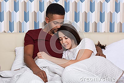 Image of beautiful loving couple laying in bed in morning, spending time together, relaxing at weekend, have good relationship, Stock Photo