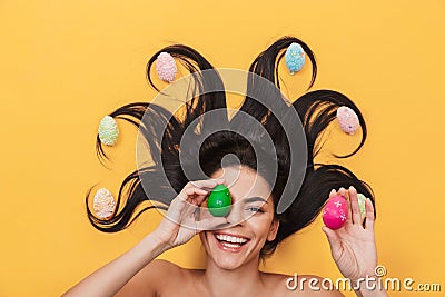 Pleased happy young woman lies isolated on yellow background over easter eggs Stock Photo