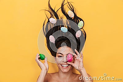 Pleased happy young woman lies isolated on yellow background over easter eggs Stock Photo
