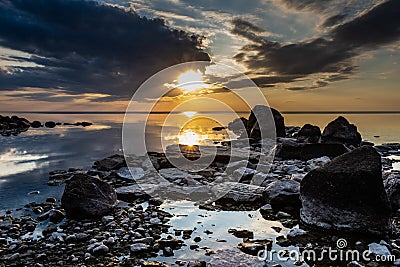 An image of a calm lake with a rocky shore at sunset. Stock Photo