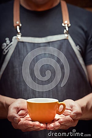 Image of Caucasian man holding with both hands orange cup of coffee. copy space Stock Photo