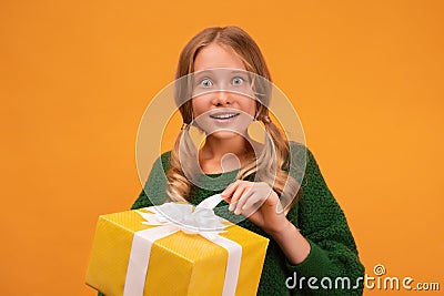 Image of charming blonde teen smiling and holding present box with white bow. New Year birthday holiday concept Stock Photo