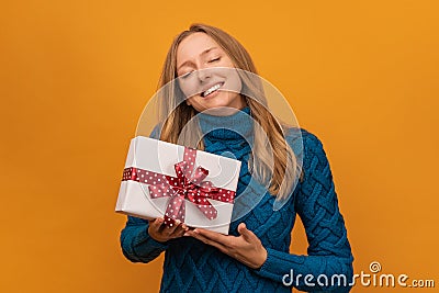 Image of charming young woman smiling and holding gift with red ribbon. New Year, Birthday, Holiday concept Stock Photo