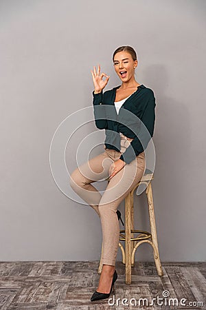 Happy business woman standing over grey wall background showing okay gesture. Stock Photo