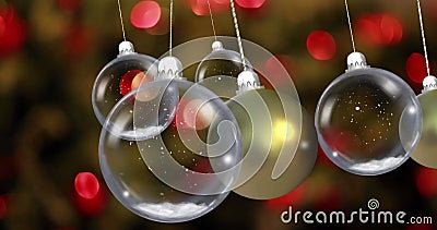 Image of christmas baubles dangling over fairy lights flickering in background Stock Photo