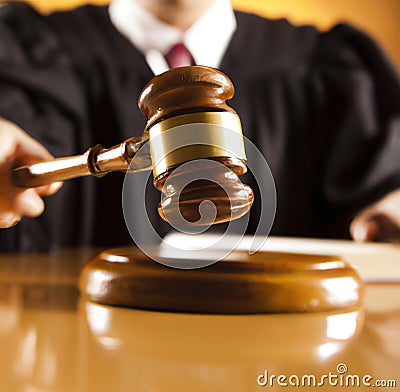 Image of close up of judge holding slamming gavel on brown background Stock Photo