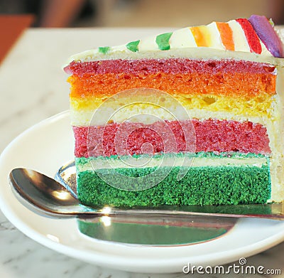 Image of close up of slice of rainbow cake with multi coloured layers on plate Stock Photo
