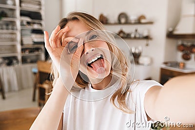 Image closeup of amusing blond woman looking at camera and taking selfie photo in living room Stock Photo