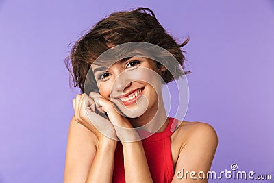 Image closeup of caucasian satisfied girl 20s in casual wear smiling and holding hands at face, isolated over violet background Stock Photo