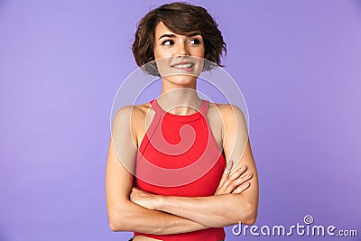 Image closeup of pretty brunette woman 20s in casual wear smiling while standing with arms crossed, isolated over violet Stock Photo