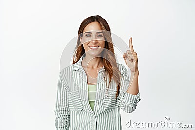 Image of confident, ambitious smiling woman, pointing finger up and looking determined, showing logo banner Stock Photo