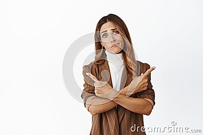 Image of confused woman asking for advice with choice, pointing sideways, looking at camera indecisive, picking between Stock Photo