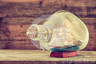 Image of decorative boat in the bottle on wooden table. nautical concept. retro filtered image Stock Photo