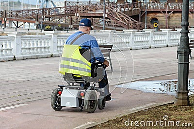 Disabled person in an electric wheelchair on the street Editorial Stock Photo