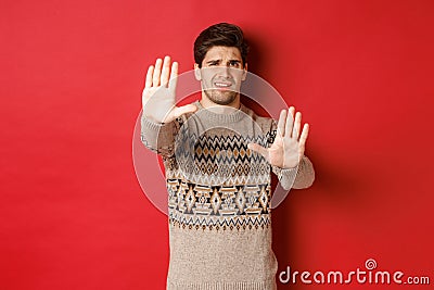 Image of disappointed handsome man, asking to stop, rejecting something awful, standing displeased against red Stock Photo