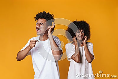 Image of displeased girl plugging her ears while her friend making fun Stock Photo