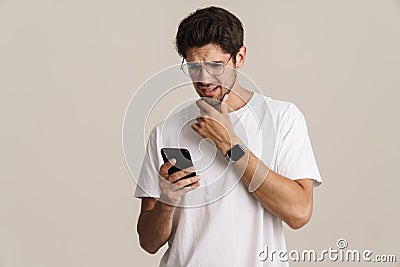 Image of displeased young man in eyeglasses using mobile phone Stock Photo