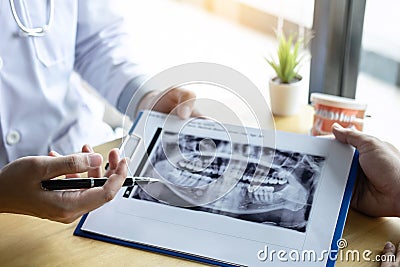 Image of doctor or dentist presenting with tooth x-ray film recommend patient in the treatment of dental and dentistry, working at Stock Photo