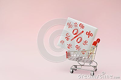 Image of empty shopping trolley or cart with box of discount percent sale black Friday products on pink background Stock Photo