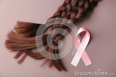 Braided strands and pink ribbon on color background. Concept of hair donation for breast cancer patients Stock Photo