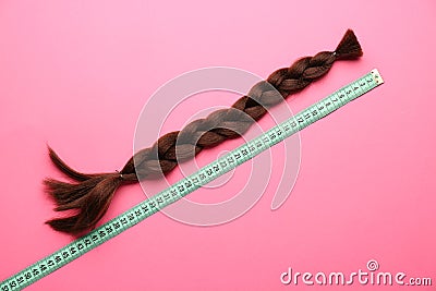 Braided strand and measuring tape on color background. Concept of hair donation Stock Photo