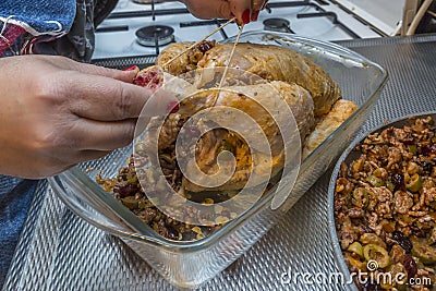 Image of female hands tying with string the legs of a raw and fresh whole chicken before being baked Stock Photo