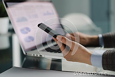 Image of female hands using mobile phone app for synchronizing data with netbook via bluetooth. Stock Photo