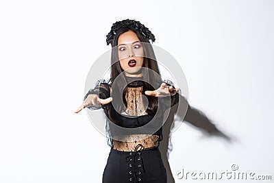 Image of funny and beautiful woman acting like undead widow, wearing black lace dress and wreat, looking like zombie and Stock Photo