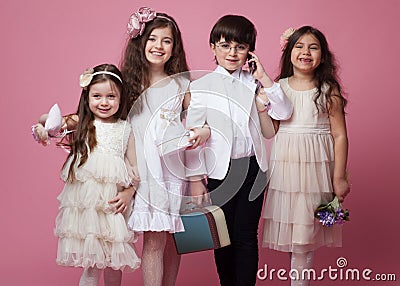 Frontal portrait of a group of happy children dressed in beautiful classic clothing, isolated on pink background. Stock Photo