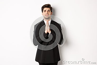 Image of handsome businessman in suit need help, begging you, holding hands in plead gesture and looking desperate Stock Photo