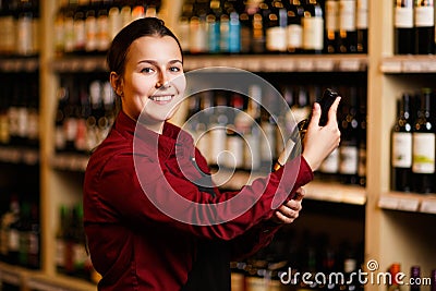 Image of happy woman with bottle in her hands in wine shop Stock Photo