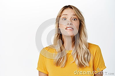 Image of hopeful cute blond girl yearning, want, look with desire and hope, stands in yellow t-shirt over white Stock Photo