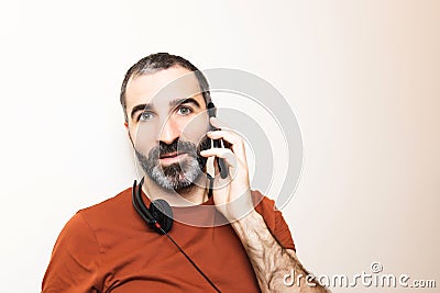 Image of an isolated young white man with beard, doing a call as a part of his job at home Stock Photo