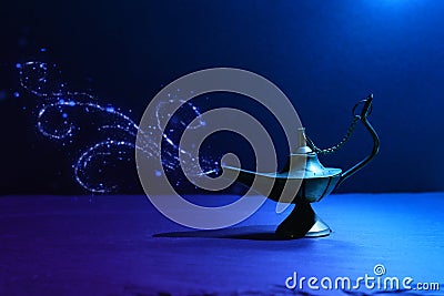 Image of magical mysterious aladdin lamp with glitter smoke. Dark background and dramatic light Stock Photo