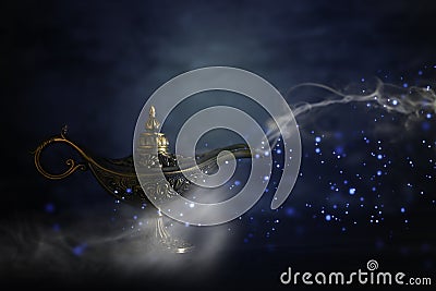 Image of magical mysterious aladdin lamp with glitter sparkle smoke over black background. Lamp of wishes. Stock Photo