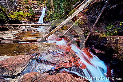 Majestic falls in background with cascading falls over red rocks in front Stock Photo