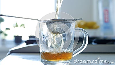 Image with Making a Hot and Aromatic Tea Using a Strainer and Natural Tea Leafs Stock Photo